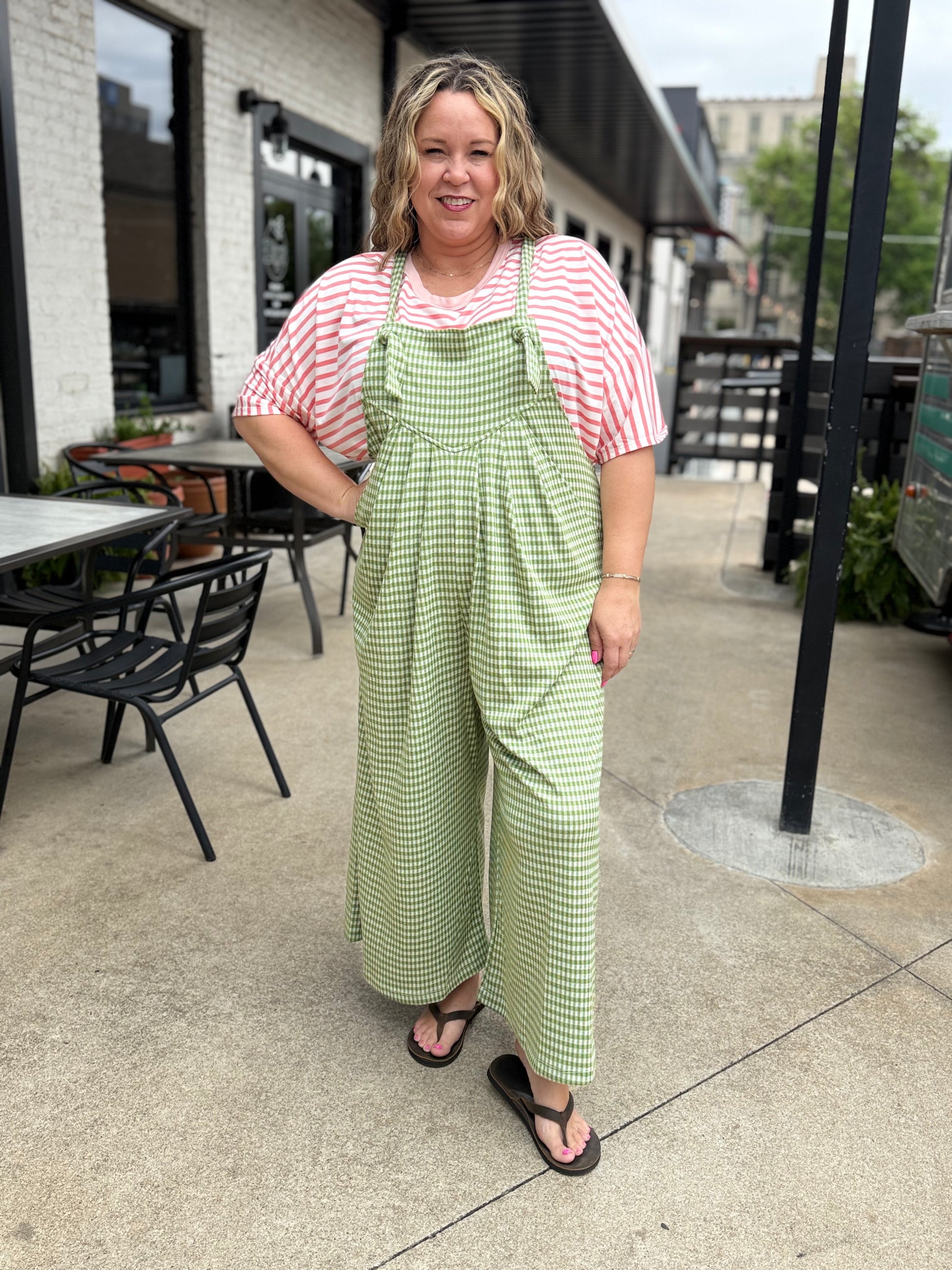 Woman wearing a green checkered dress over a red and white striped shirt outdoors.